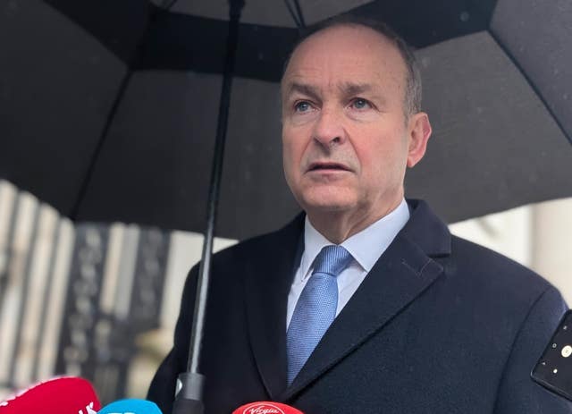 Micheal Martin standing under an umbrella while speaking to reporters
