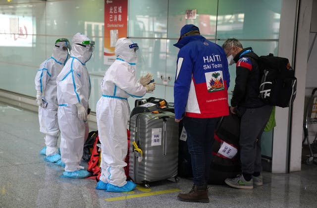 Airport staff wearing hazmat suits assist passengers at Beijing International Airport 