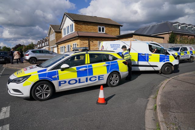 A police car and a police van in the road at the scene in Bushey