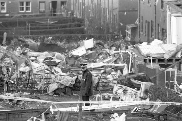 A policeman stands guard over houses damaged in the Pan Am Boeing 747 Lockerbie crash