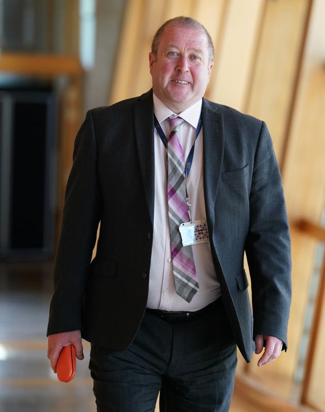 Graeme Dey smiling while walking along a Holyrood corridor