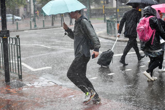 People make their way through a heavy rain shower in Birmingham