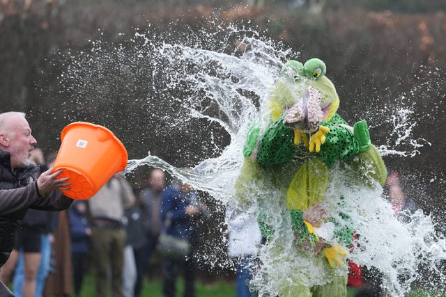 A bucket of water is thrown over two competitors dressed as frogs