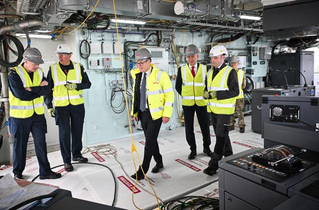 Sir Keir Starmer and John Healey wearing hi-vis clothing and hard hats amongst staff at a BAE Systems site