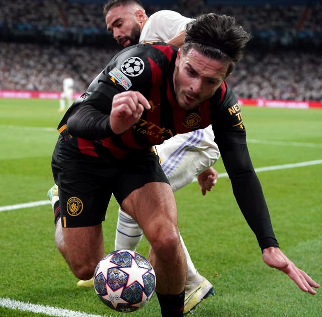 Manchester City''s Jack Grealish is shoved into the advertising hoardings by Real Madrid''s Dani Carvajal, rear