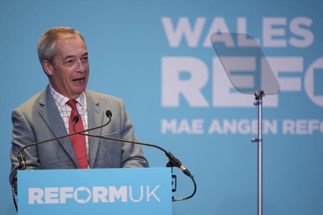 Nigel Farage speaking from behind a lectern in front of a turquoise backdrop