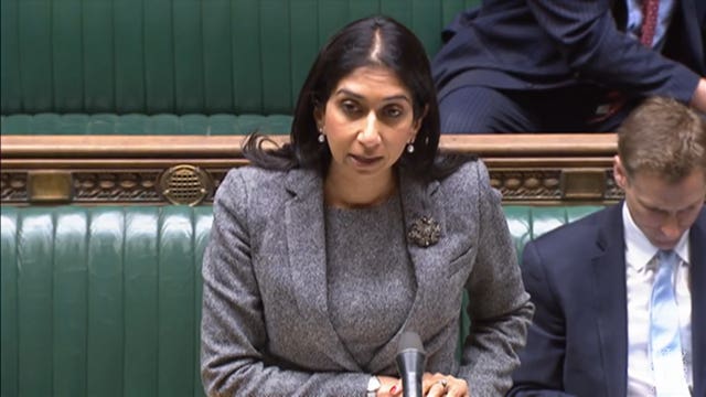 Suella Braverman standing in the House of Commons wearing a grey woollen suit.