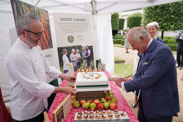 The King cuts a cake to celebrate four decades of the Prince of Wales’s Charitable Fund, with Waitrose senior chef Will Torrent, during a reception at Clarence House