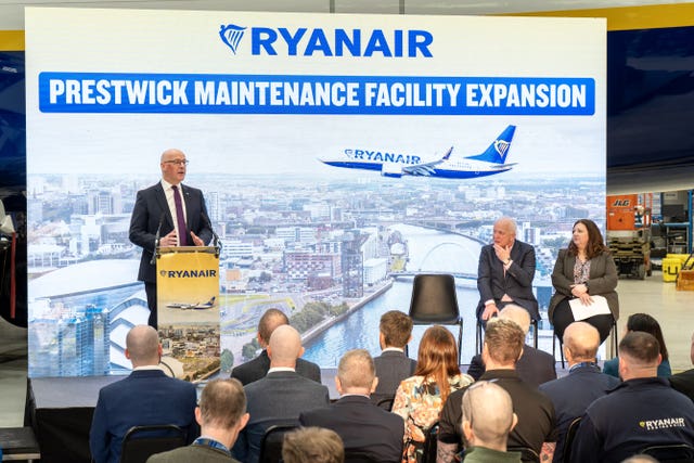 John Swinney speaking to an audience in front of Ryanair signage