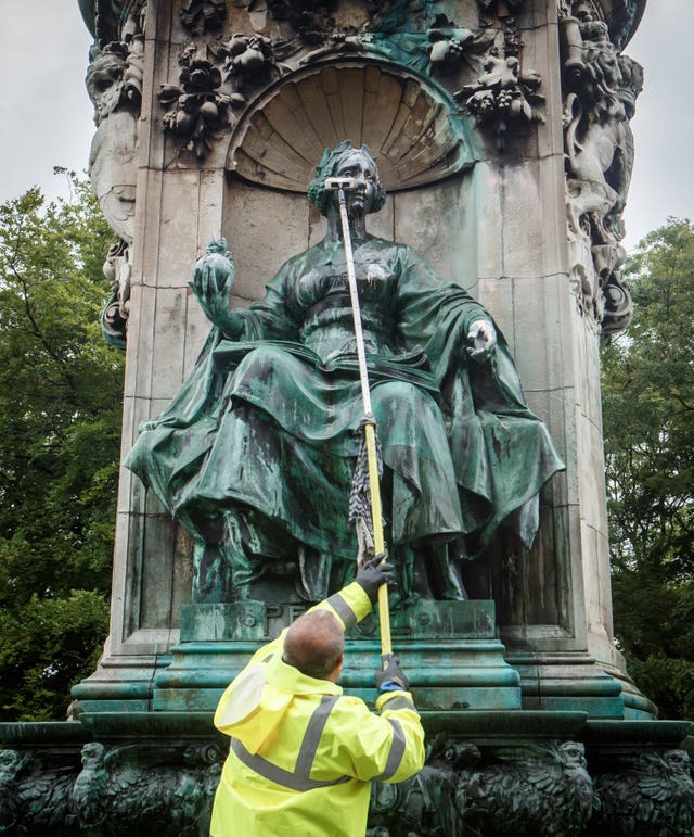 Council workers clean graffiti from a statue of Queen Victoria in Woodhouse Moor in Leeds