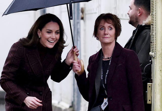 The Princess of Wales smiles as she ducks under an umbrella