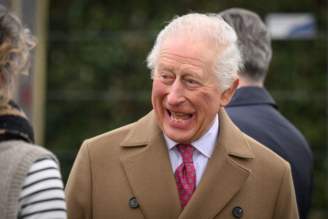 The King laughs as he speaks with volunteers during a visit to Newquay Orchard 