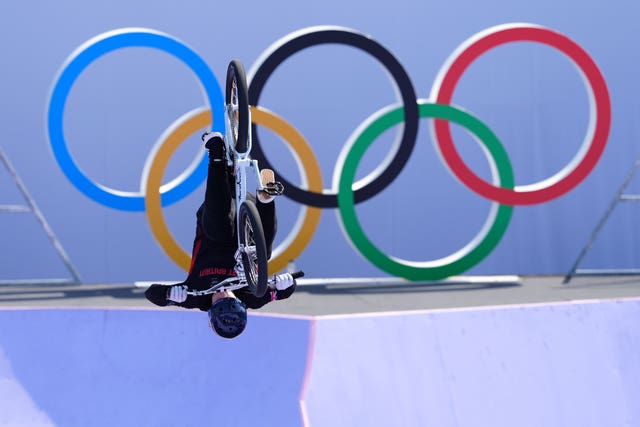 Kieran Reilly performs in the BMX, upside down with the Olympic rings as a backdrop.