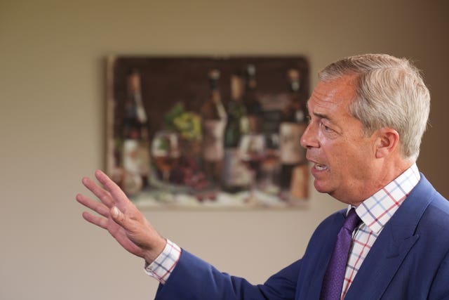 Nigel Farage dressed in a blue suit with a purple tie gestures with his right hand