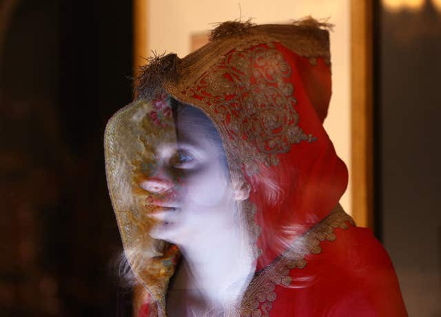 The face of a Royal Collection Trust employee reflected in the hood of Napoleon’s cloak, part of the Prince & Patron exhibition, part of the summer opening of Buckingham Palace. (Yui Mok/PA)