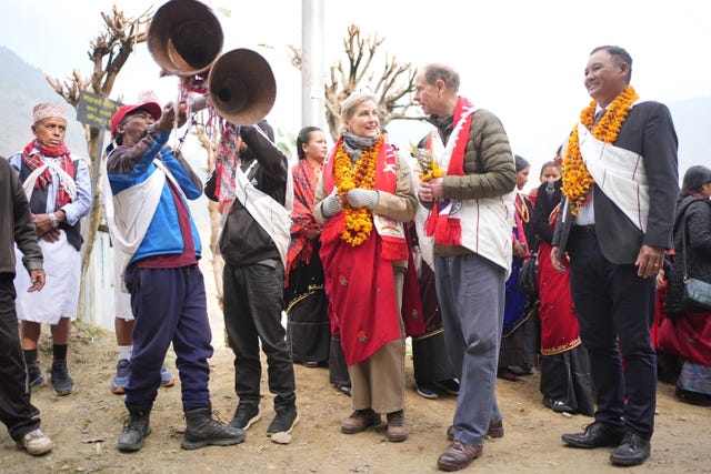 The Duke and Duchess of Edinburgh surrounded by villagers in Nepal as musicians play