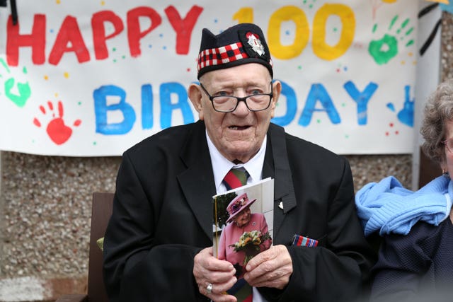 Former Royal Scots George Simpson outside his house in Danderhall, Midlothian, with his card from the Queen, to mark his 100th birthday David Cheskin/PA)