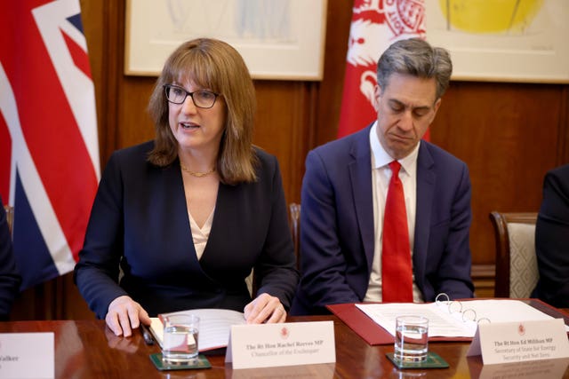 Rachel Reeves, left, speaking while sitting at a table next to Ed Miliband