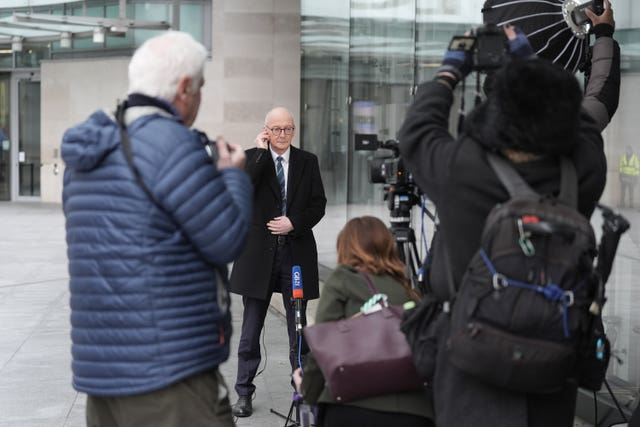 Pat McFadden standing outside BBC Broadcasting House in London being filmed and photographed by members of the media