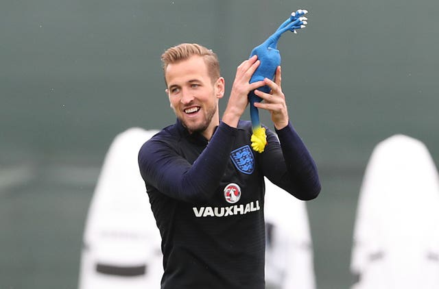 England captain Harry Kane takes hold of a rubber chicken during a game in training.
