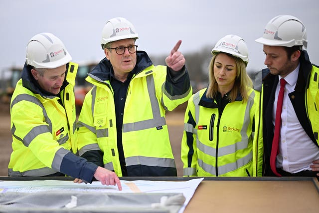 Keir Starmer in hi-vis looking at building plans surrounded by people 