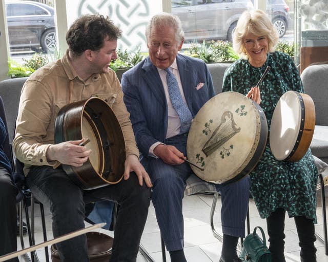 The Prince of Wales (centre) and Duchess of Cornwall play the bodhran 