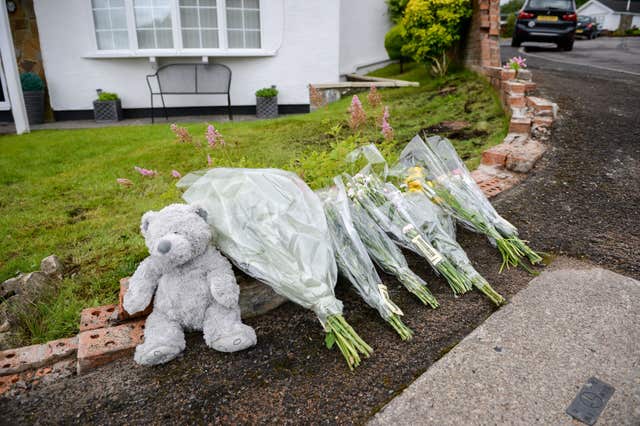 Flowers and a teddy bear lay on the remains of the collapsed wall at a property in Heolgerrig, South Wales (Ben Birchall/PA)