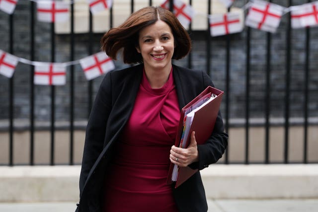 Woman holding a folder in front of black railings 