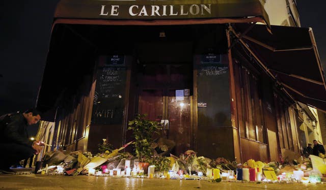 A man places a candle at the La Carillon restaurant in Paris, following the attacks which killed 130 people (Steve Parsons/PA)