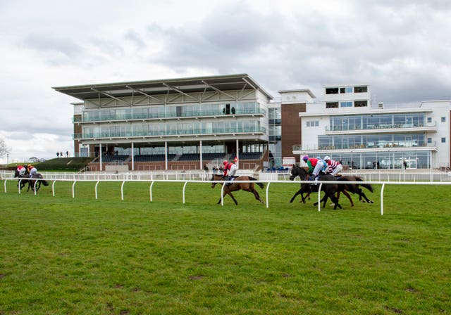Runners and riders pass the empty stands at a race meeting at Wetherby on Tuesday