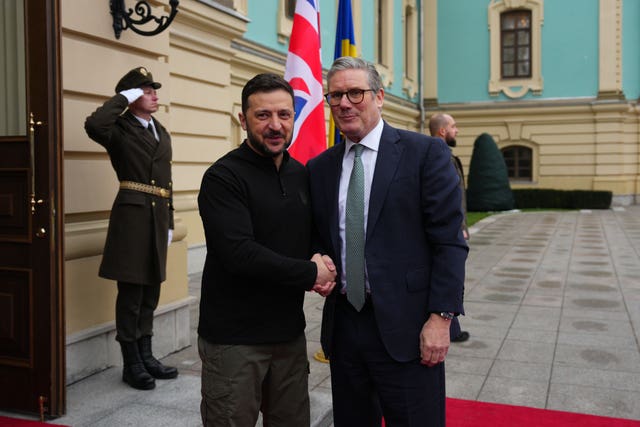 Volodymyr Zelensky and Sir Keir Starmer shake hands in Kyiv, as a soldier salutes in the background