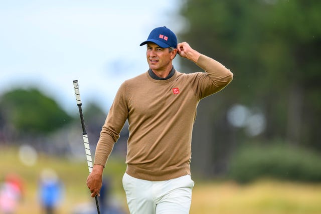 Adam Scott holds his putter and adjusts his cap