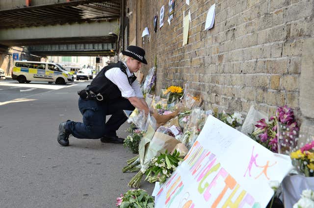 A police officer laying some flowers passed over by a member of the public, close to Finsbury Park Mosque in north London, in 2017