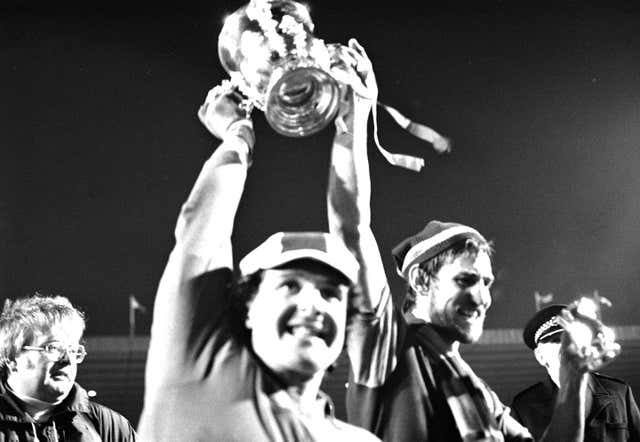 Aston Villa captain Chris Nicholl, who scored their first goal, and goalkeeper John Burridge raise the League Cup after victory over Everton