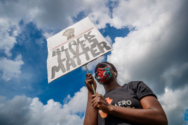 A woman holds a banner during a Black Lives Matter protest rally at Woodhouse Moor in Leeds