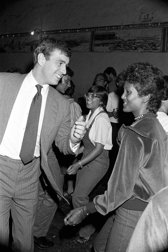 Black and white photo taken in 1984 of Andrew dancing, in a group of people