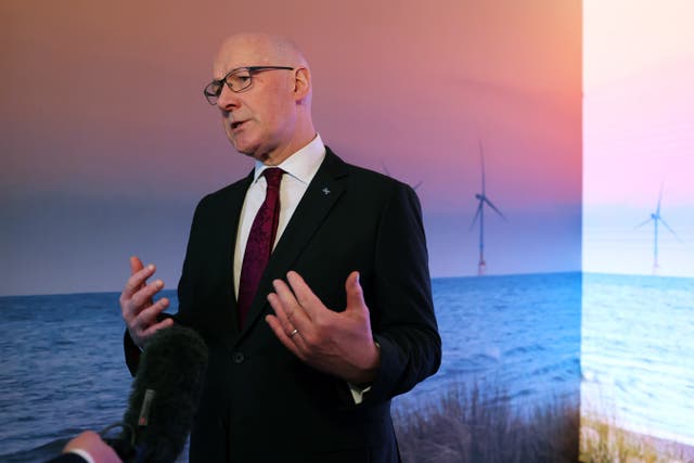 John Swinney gesturing with coastal backdrop