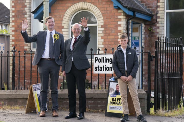 John Swinney with his son and an SNP candidate outside a polling station