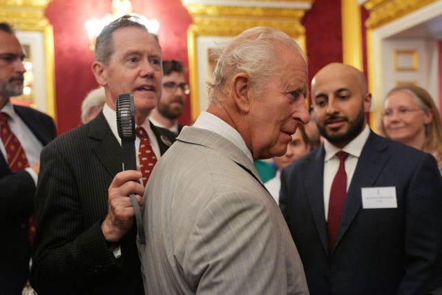 An aide holds a fan close to the King
