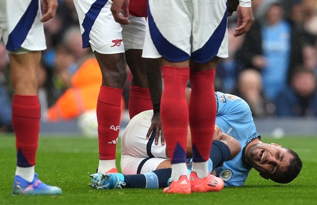 Rodri lies on the floor in pain surrounded by Arsenal players after suffering a knee injury