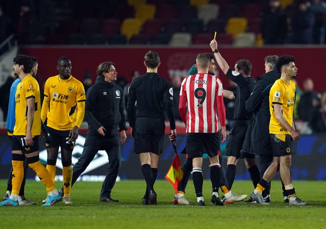 Thomas Frank, centre left, receives his first yellow card from referee Peter Bankes after Brentford's loss to Wolves