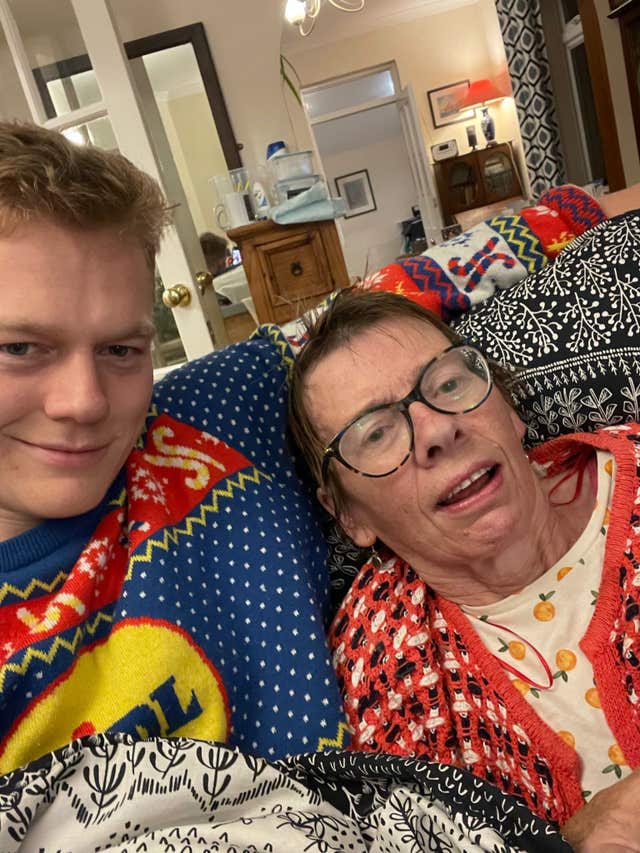 Man dressed in Lidl Christmas jumper and sat next to his mother who is wearing glasses