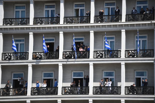 People watch from balconies of a building overlooking the Independence Day Military Parade in Syntagma Square 