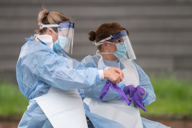 NHS staff put on personal protective equipment before carrying out Coronavirus tests at a testing facility in Bracebridge Heath, Lincoln (Joe Giddens/PA)