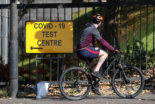 A cyclist passes a Covid-19 test centre sign (Andrew Milligan/PA)