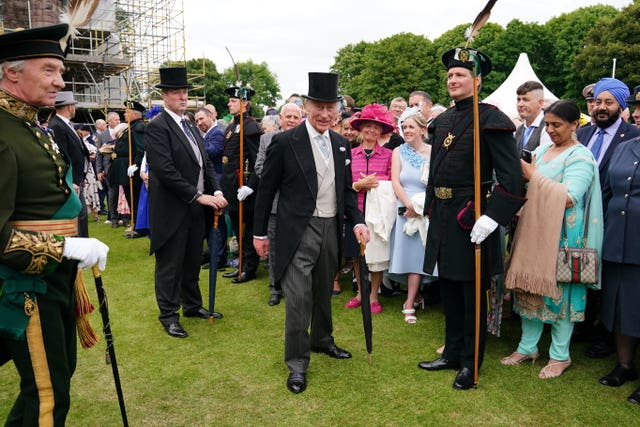 The King in a top hat and tails surrounded by guests 