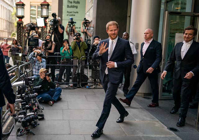 Harry waves as he leaves the Rolls Buildings in London