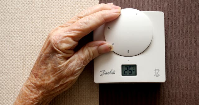 An elderly lady adjusting her thermostat