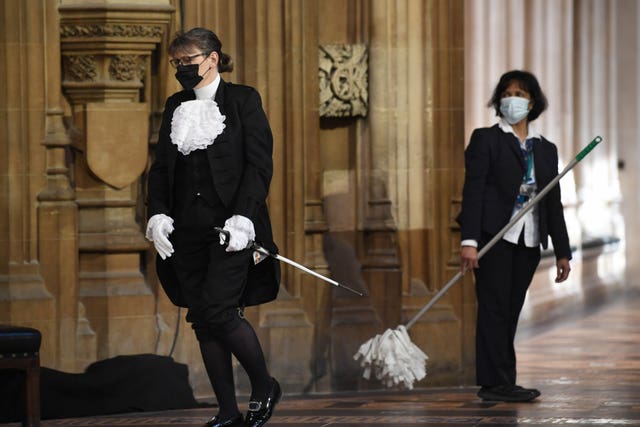 A parliamentary official walks past a cleaner in the Central Lobby