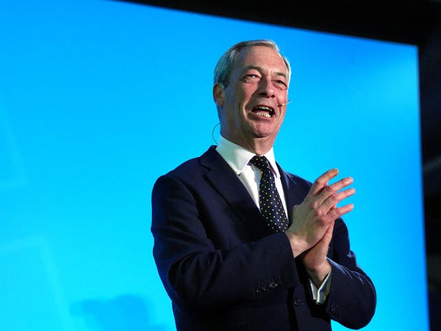 Nigel Farage rubs his hands together during a speech at a Reform UK conference